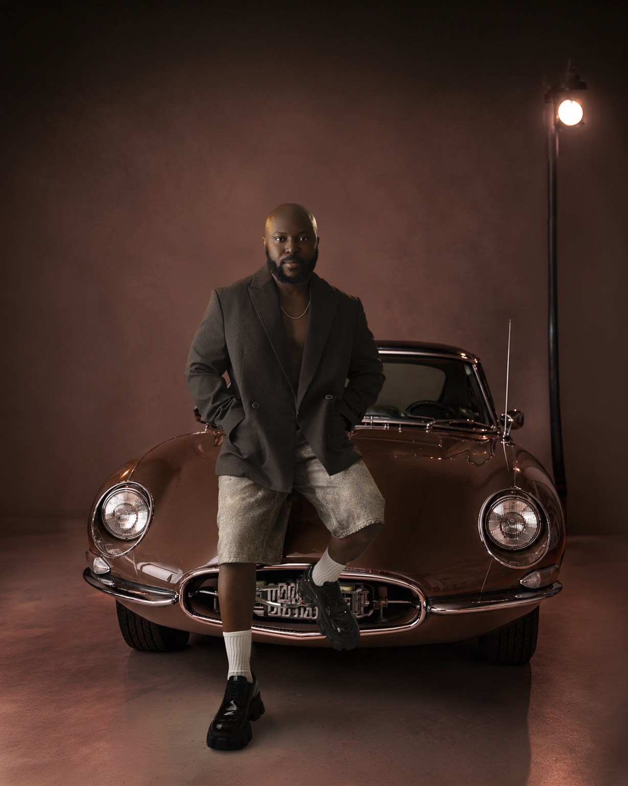 SauciBossy standing in front of a vintage car