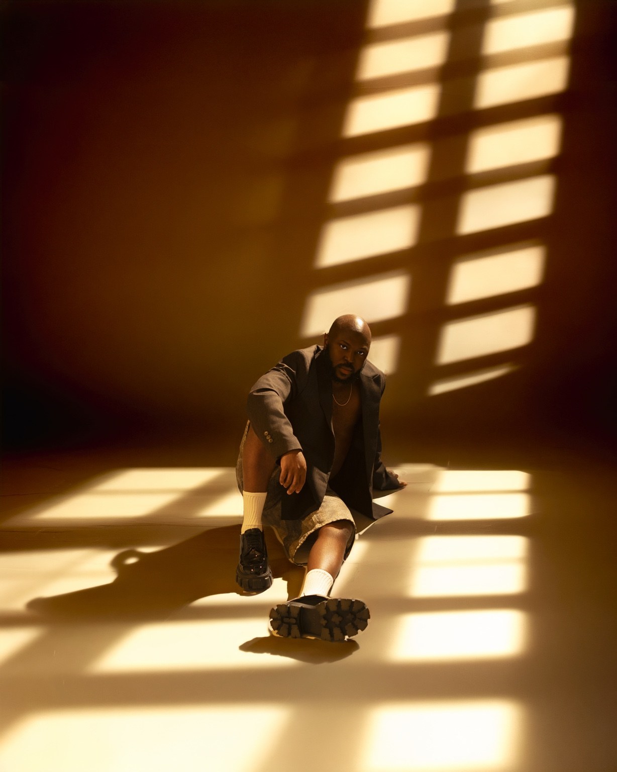 SauciBossy seated in warm light and window shadows